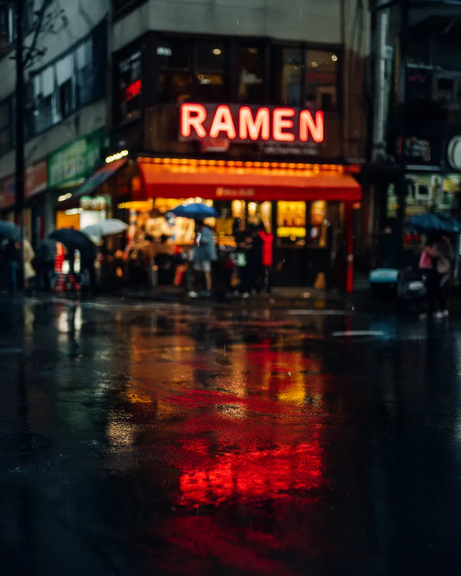 Rua chuvosa de Tóquio à noite com um letreiro neon vermelho RAMEN e pessoas segurando guarda-chuvas.