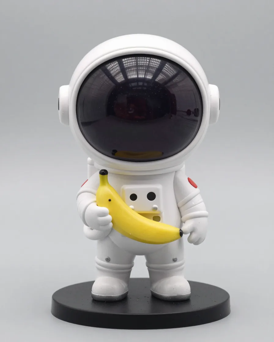 Boneco colecionável de vinil brilhante de um astronauta segurando uma banana sobre uma base redonda.